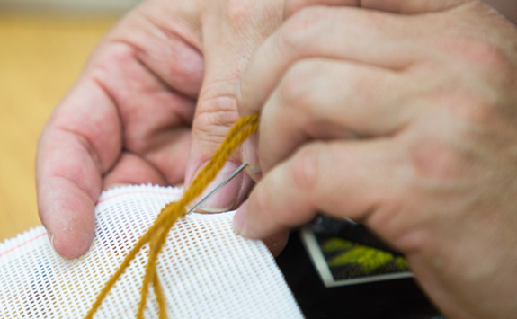 Hands sewing with yellow thread